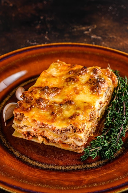 Italian Lasagne with tomato bolognese sauce and mince beef meat on a rustic plate. Dark background. Top view.