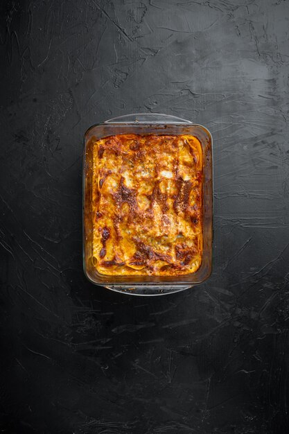 Lasagne italiane con salsa bolognese di pomodoro e carne di manzo tritata, in teglia, su pietra nera