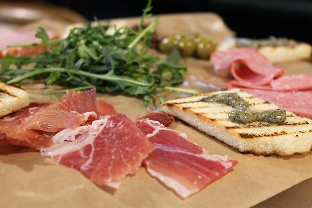 Italian meat plate, jamon, arugula, pesto toast, sausage cuts, olives, black olives, carbonade, cold