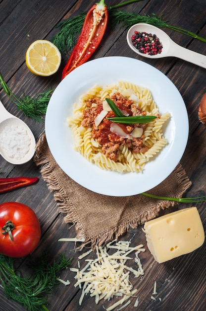 Pasta al sugo di carne italiana e deliziosi ingredienti freschi per cucinare su fondo rustico.