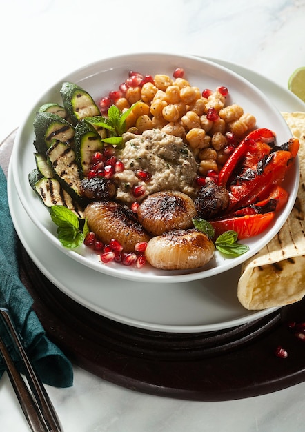 Italian Mediterranean Buddha bowl with Baba ghanoush caramelized onions spicy chickpeas and grilled vegetables healthy vegan food and pita bread