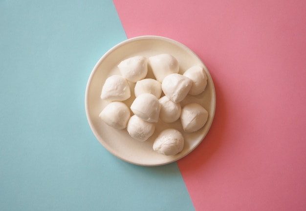 Italian mozzarella cheese balls on the blue-pink background.