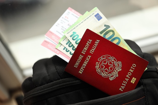 Фото Итальянский паспорт и банкноты евро с авиабилетами на рюкзаке вблизи