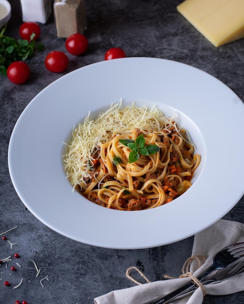 Italian Pasta Bolognese on a white plate with ingredients on a dark background restaurant menu