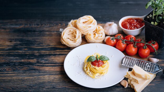 Italian pasta bolognese with grated parmesan and basil closeup ingredients in the background