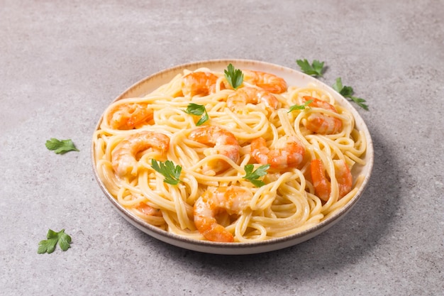 Italian pasta fettuccine or spaghetti in a creamy cheese sauce with shrimp or prawns on a plate