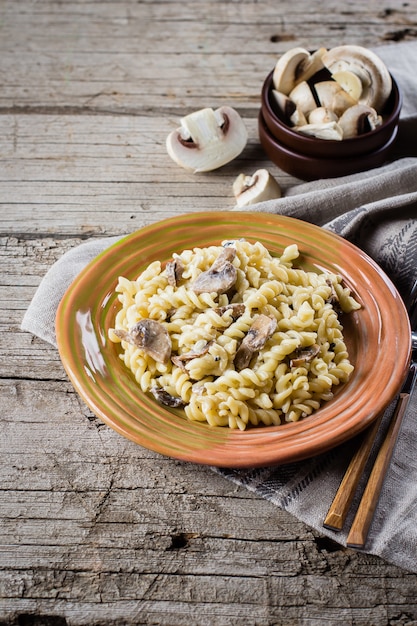 Fusilli italiano della pasta con i funghi e la salsa crema sulla tavola di legno, spazio della copia, vista superiore.