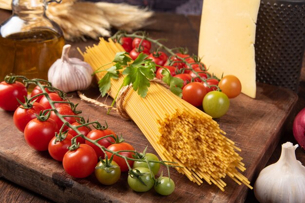 Italian pasta (macaroni),  tomatoes, olive oil, cheese and spices on rustic wood