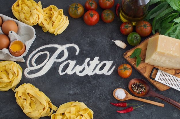 Italian pasta and sauce ingredient  with text made from flour, top view on dark background