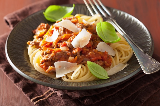 Italian pasta spaghetti bolognese with basil on rustic table