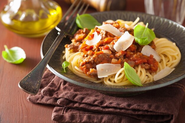 Italian pasta spaghetti bolognese with basil on rustic table