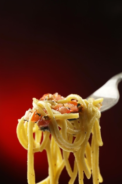 Italian pasta spaghetti on fork on dark background