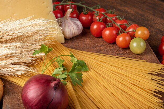 Italian pasta, spaghetti, tomatoes, olive oil, cheese and spices on rustic wood