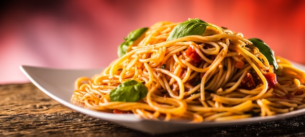 Italian pasta spaghetti with tomato sauce basil and parmesan cheese in white plate.