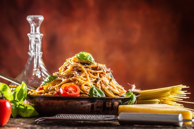 Итальянская паста спагетти с томатным соусом, базиликом оливкового масла и сыром пармезан в старой сковороде.