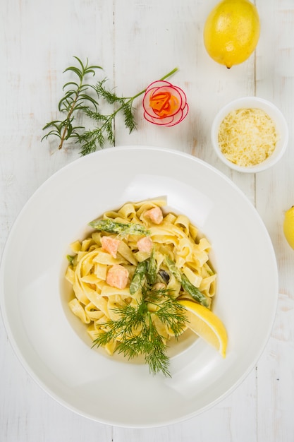 Photo italian pasta with salmon and herbs on white table