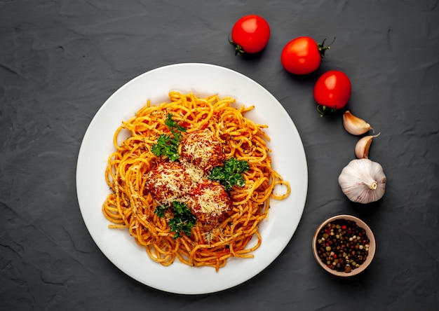 Italian pasta with tomato sauce and meatballs in a plate on a stone background