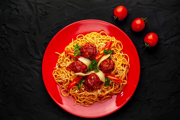 Foto pasta italiana con salsa al pomodoro e polpette in un piatto con le spezie sulla pietra