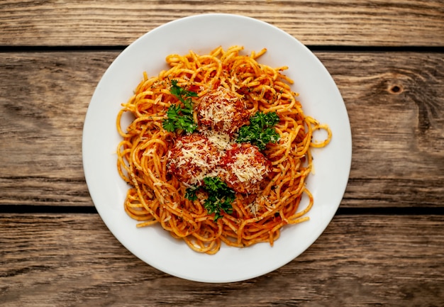 Foto pasta italiana con salsa al pomodoro e polpette in un piatto con le spezie su legno