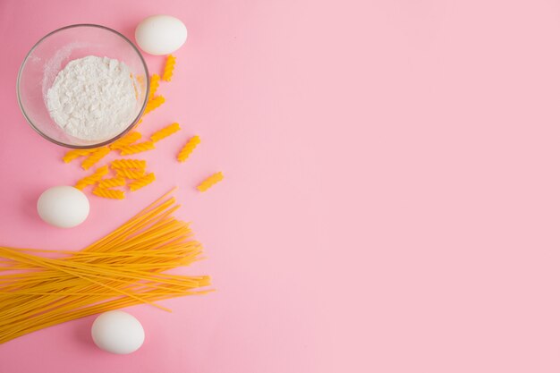 Italian pasta. Yellow long spaghetti and pasta on pink background.