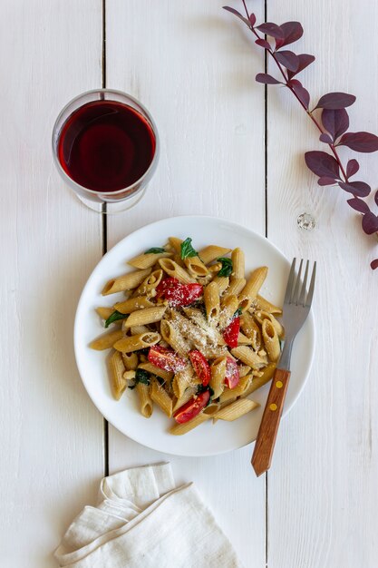 Italian penne pasta with tomatoes, spinach, parmesan cheese, garlic and nuts. Healthy eating. Vegetarian food.