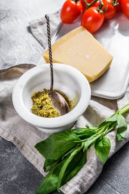 Italian  Pesto in marble mortar, Basil leaves and Parmesan on a chopping Board. Space for text