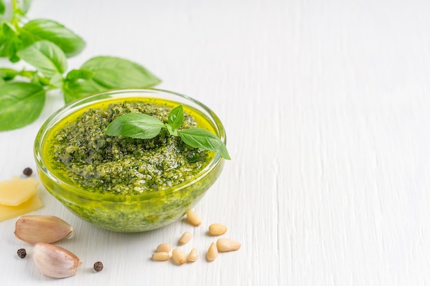 Pesto italiano a base di foglie di basilico pinoli aglio parmigiano e olio d'oliva in una ciotola di vetro