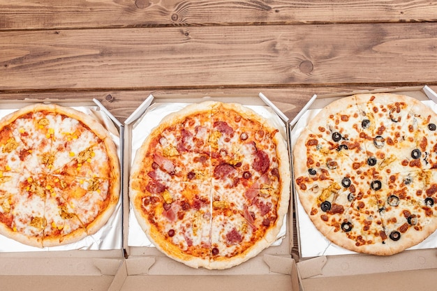 Foto pizza italiana in scatola di cartone su tavola di legno vista dall'alto