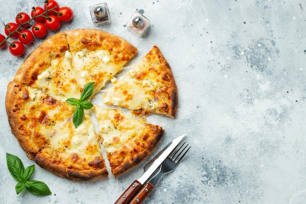 Photo italian pizza four cheeses with stretching cheese and basil on a light concrete background