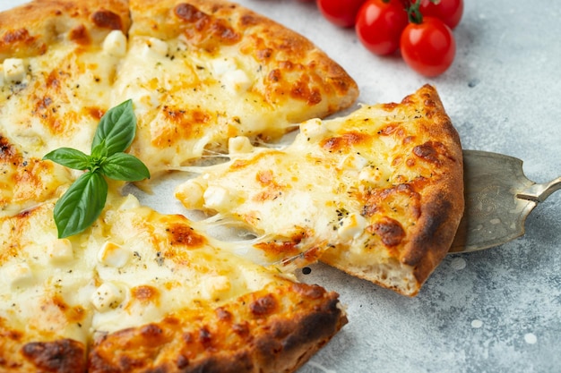 Italian pizza four cheeses with stretching cheese and basil on a light concrete background