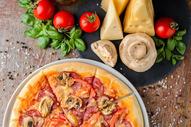 Pizza italiana e ingredienti su legno, vista dall'alto