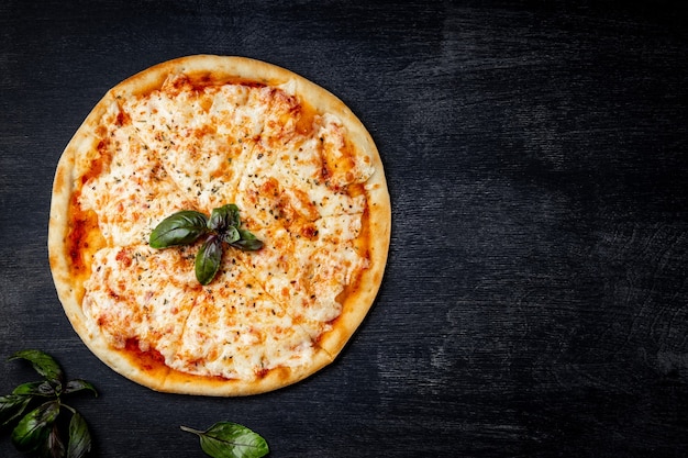 Foto pizza italiana margarita su sfondo nero, vista dall'alto, spazio libero per il testo.