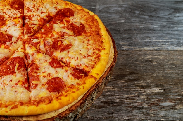 Italian pizza peperoni with salami and mozzarella cheese on wooden table