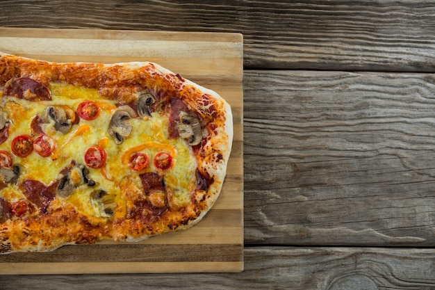 Italian pizza served on chopping board on a wooden plank