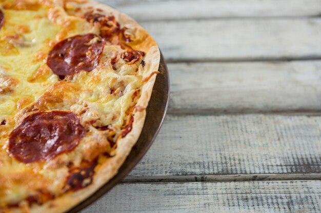 Italian pizza served in a tray on a wooden plank