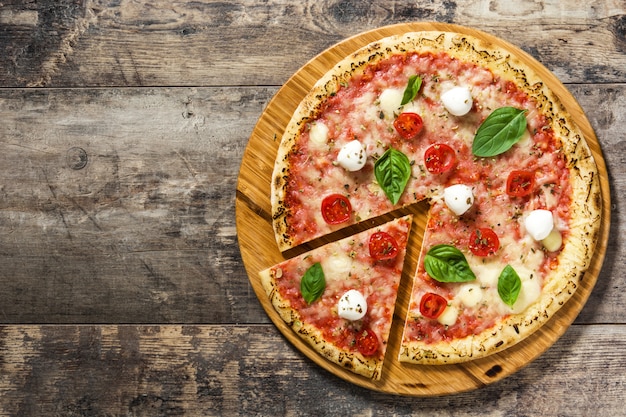 Italian pizza slice with tomatoes, cheese and basil on wooden table Top view copy space