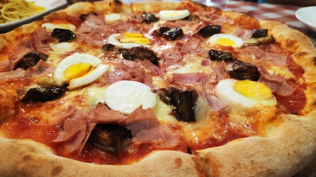 Italian pizza with eggplants hot salami and eggs