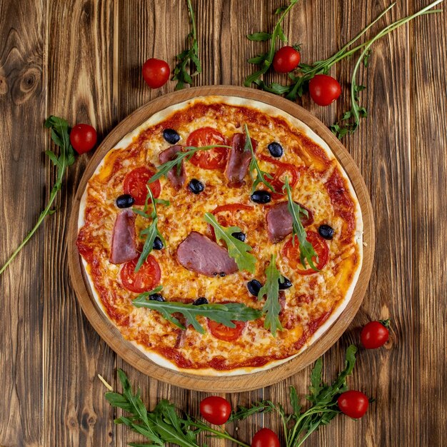 Photo italian pizza with ham tomatoes olives and basil on wooden table top view with copy space