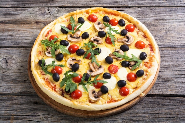 Italian pizza with mozzarella tomato olives and mushrooms arugula