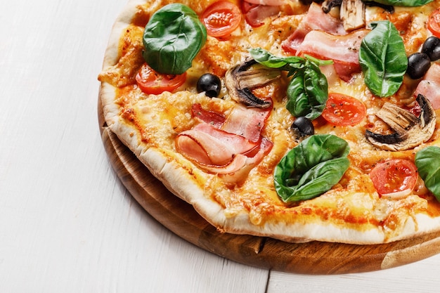 Italian pizza with mushrooms, basil, tomato, olives and cheese