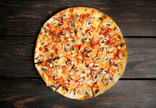 Pizza italiana con funghi, pomodori e formaggio su legno