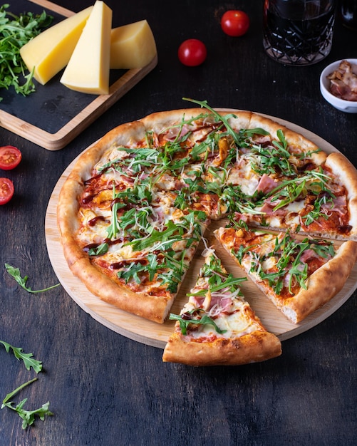 Italian Pizza with Parma ham and arugula cherry tomatoes and bacon on a wooden background