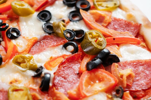 Italian pizza with salami jalapena olives and tomatoes Cooking concept in the style of Italian cuisine