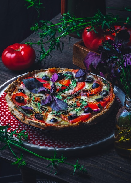 Italian pizza with tomatoes mozzarella cheese olives on old wooden background