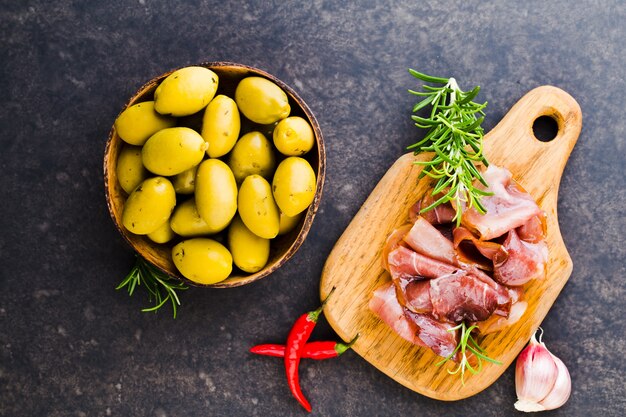 Italian prosciutto crudo or jamon with spice, olive, rosemary. Raw ham.