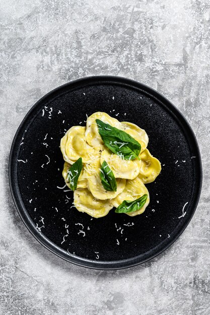 Foto ravioli italiani con formaggio e basilico. sfondo grigio. vista dall'alto