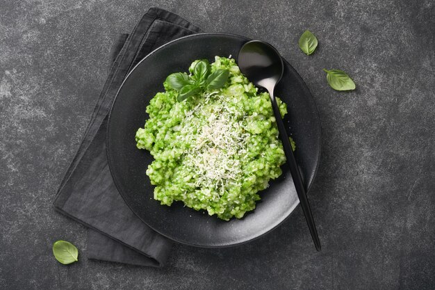 Italian risotto Delicious risotto with pesto sauce or wild garlic pesto basil parmesan cheese and glass of white wine on dark slate table background Italian dinner Top view with copy space