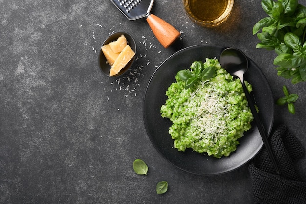 Italian risotto delicious risotto with pesto sauce or wild
garlic pesto basil parmesan cheese and glass of white wine on dark
slate table background italian dinner top view with copy space