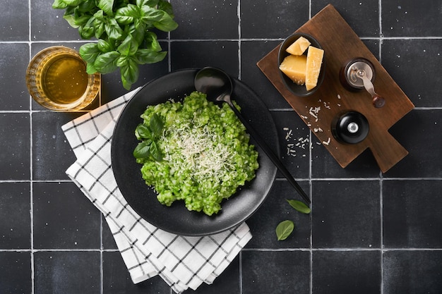 Italian risotto Delicious risotto with pesto sauce or wild garlic pesto basil parmesan cheese and glass of white wine on old black tiles table background Italian dinner Top view with copy space