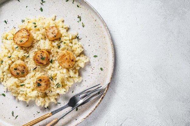 Foto risotto italiano con capesante di mare scottate in padella.